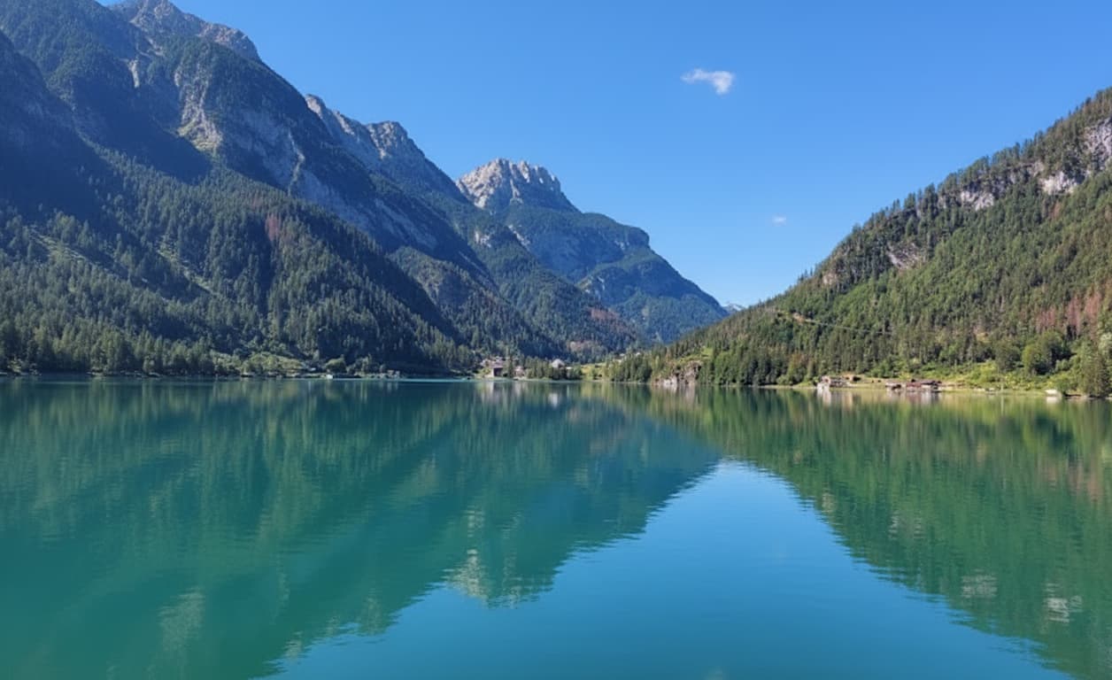 Vista panoramica del Lago di Braies con le vette dolomitiche riflesse nell'acqua alpina al mattino.